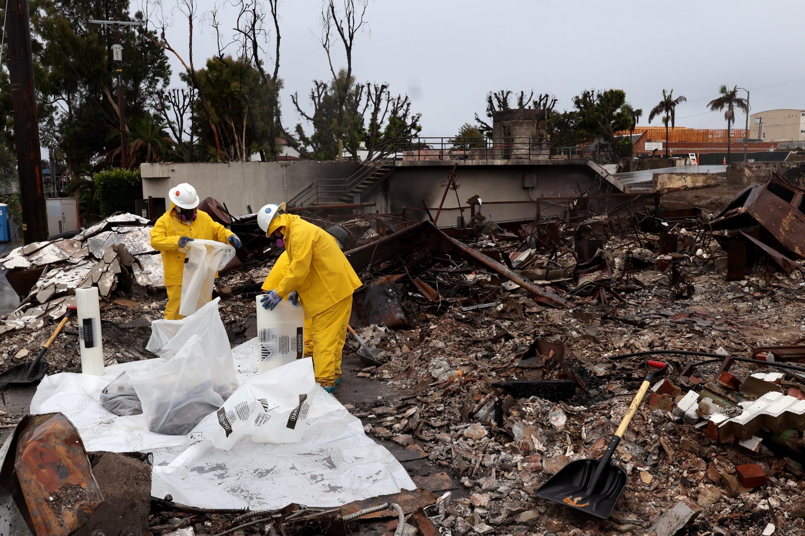 Workers clear debris from a business destroyed by the Palisades fire