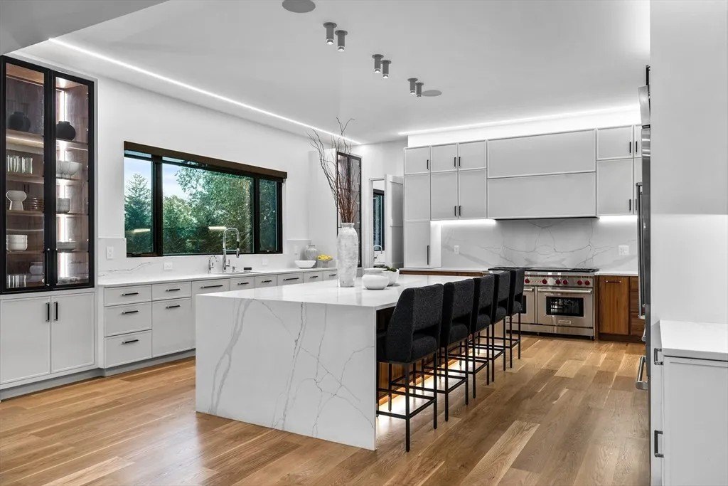 NBA Star Jrue Holiday Lists His Massachusetts Home For $6.9 Million—Weeks After Portland Trail Blazers Kitchen with a large island and seating in a luxury home in Massachusetts that belongs to Jrue Holiday